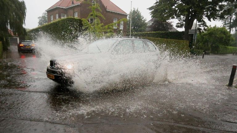 Deze automobilist liet zich niet tegenhouden door het vele water op de Torenstraat in Helvoirt (foto: Bart Meesters).