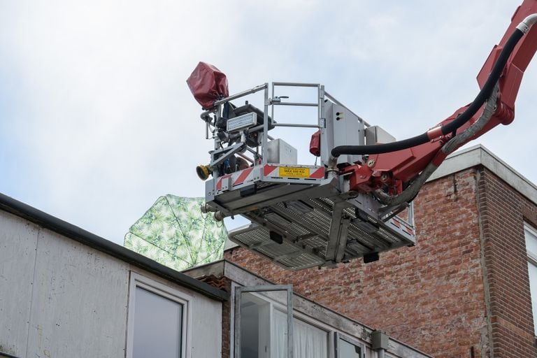 De brandweer haalt een parasol van het dak van een huis in Breda (foto: Tom van der Put/SQ Vision).