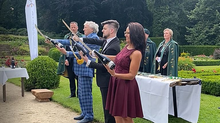 Tom sabreert vakkundig een fles champagne.