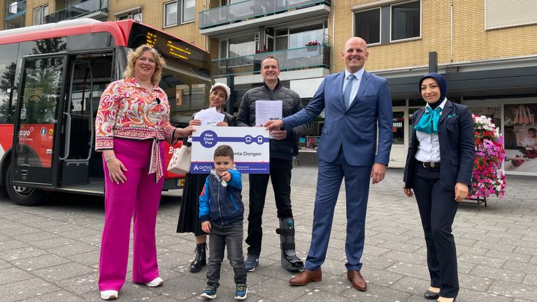 Wethouder De Hoon (l) reikt de eerste gratis buspassen uit aan Safa en Maikel (foto: Omroep Brabant).