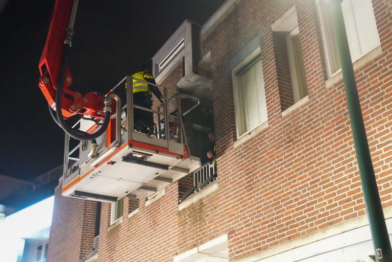 De agenten werden met een hoogwerker uit het appartement in Deurne gehaald (foto: Harrie Grijseels/SQ Vision).