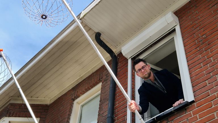 Gijs hangt de vlaggenstok met kerstverlichting weer buiten (foto: Omroep Brabant). 