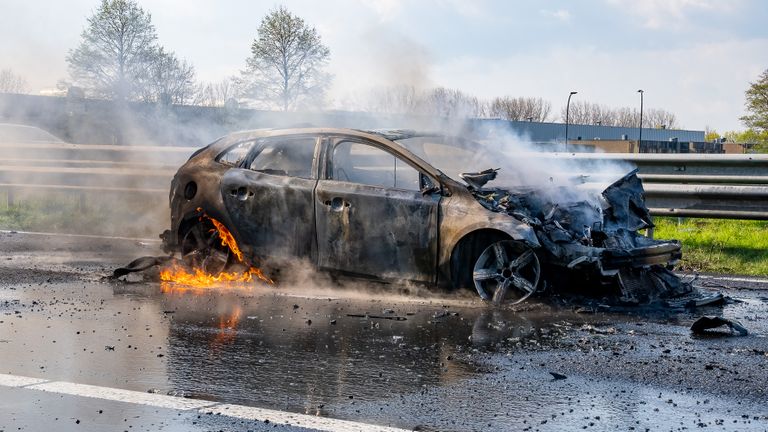 De uitgebrande wagen op het beschadigde wegdek (foto: Iwan van Dun/SQ Vision Mediaprodukties).