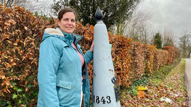 Corinne Kerremans-van de Sanden bij de grenspaal naast haar tuin (foto: Erik Peeters).