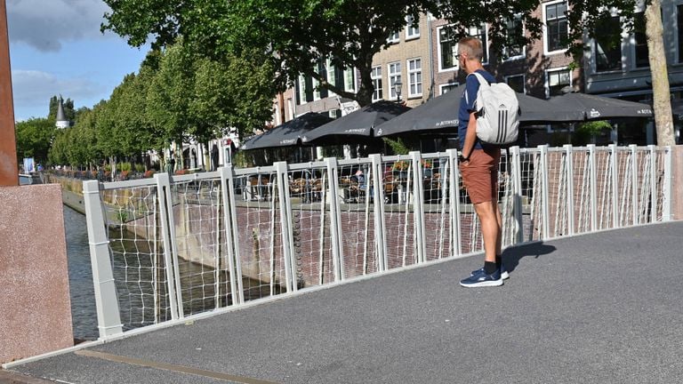 Een man kijkt uit over de beveiligde brug (foto: Perry Roovers/Persbureau Heitink).