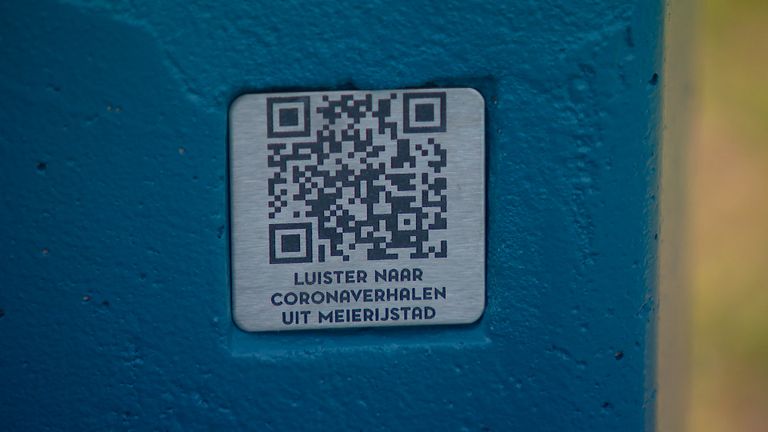 Op het bankje zit een plaatje met QR-code om naar de podcast te kunnen luisteren.