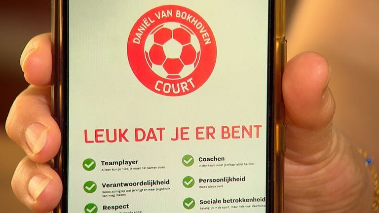 Moeder Yvonne laat zien hoe de tekst er op het bord uit komt te zien.