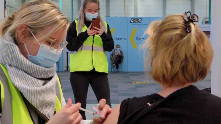 Op verzoek van een verpleegkundige uit Son zet een GGD-medewerkster haar op de foto terwijl ze wordt gevaccineerd (foto: Joris van Duin).