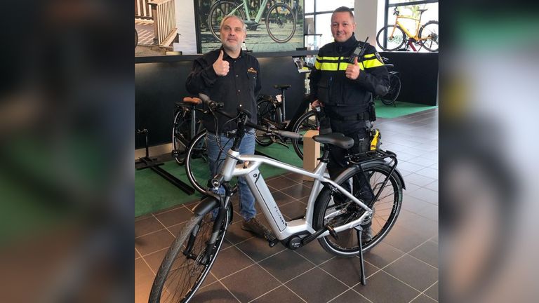De eigenaar van de winkel en een agent zijn blij dat de fiets terug is (foto: Basisteam Peelland).