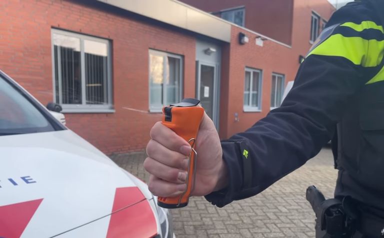 Een agent demonstreert de UV-spray (foto: Facebook politie Rooendaal).