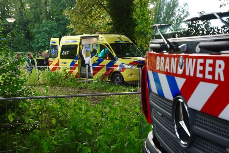 Een man die in Sint-Michielsgestel in de Dommel terecht was gekomen, werd door ambulancemedewerkers en de politie opgevangen (foto: Sander van Gils/SQ Vision).