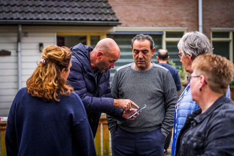 Buurtbewoners kijken naar een foto van de antitankgranaat (foto: SQ Vision).