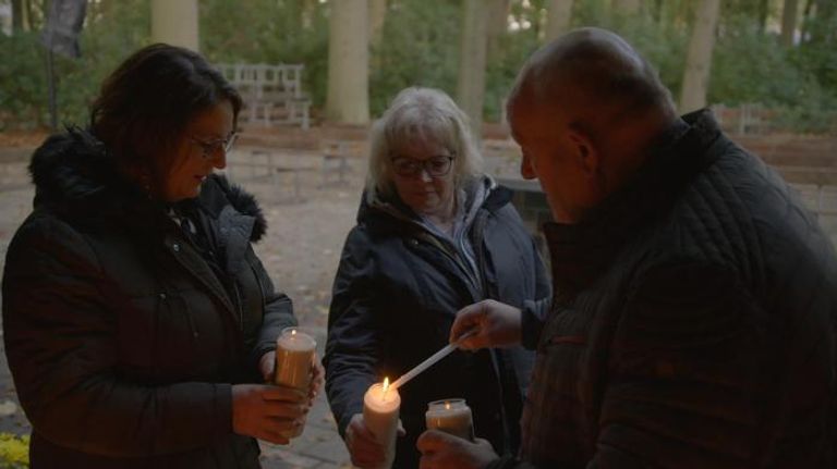 Hans steekt met zijn vrouwen een kaarsje op bij een kapelletje