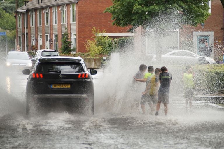 Kinderen worden nat gespat in de ondergelopen straten (Foto: Erik Haverhals).