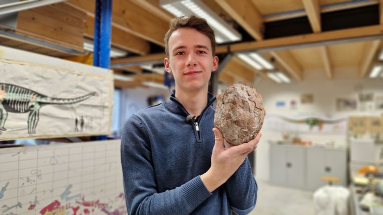 Curator Maarten de Rijke met ei van dinosaurus. 