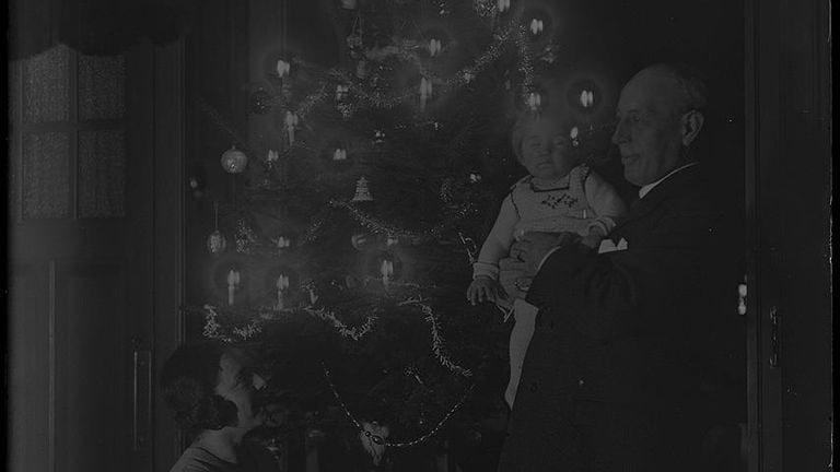 Jo Halbertsma kijkt omhoog naar een man en kindje naast de kerstboom. De foto is genomen tussen 1920-1925 (foto: Stedelijk Museum Breda).