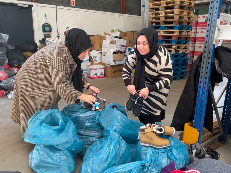 Vrijwilliger Fatima (links) sorteert schoenen uit met een vriendin