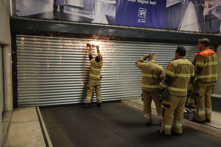 De brandweer zaagt de rolluiken open (foto: Bart Meesters/SQ Vision).