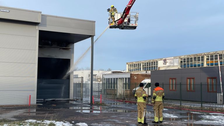 De brandweer blust door middel van openingen in het pand de brand (foto: Imke van de Laar).