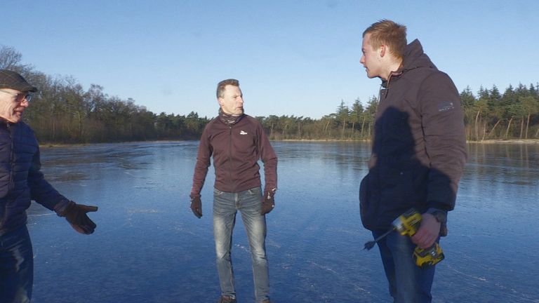 Hans en twee andere schaatsliefhebbers meten hoe dik het ijs is. 