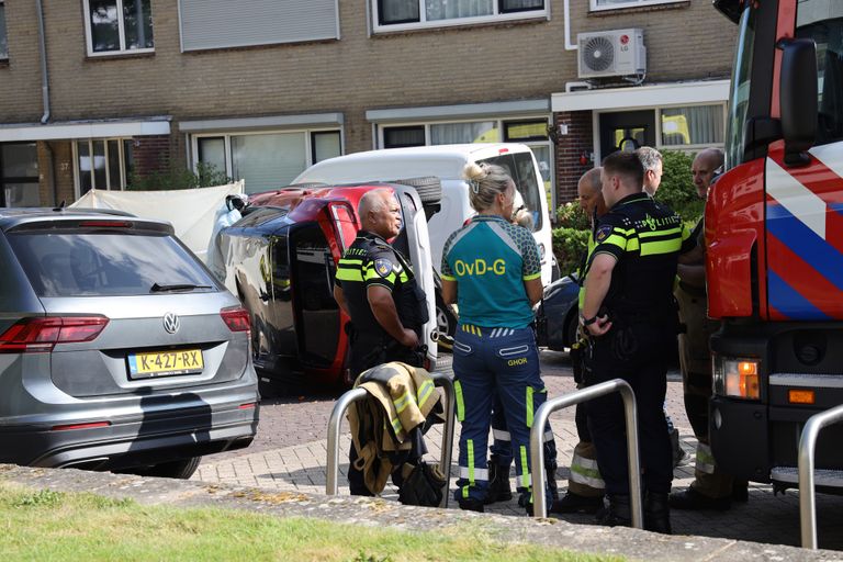 De man raakte met zijn auto een aantal geparkeerde auto's en sloeg daarna met zijn auto om (foto: Marco van den Broek/SQ Vision).