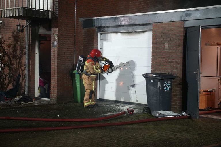 De brandweer moest ook een garagedeur open zagen om bij het vuur te komen (foto: SQ Vision).