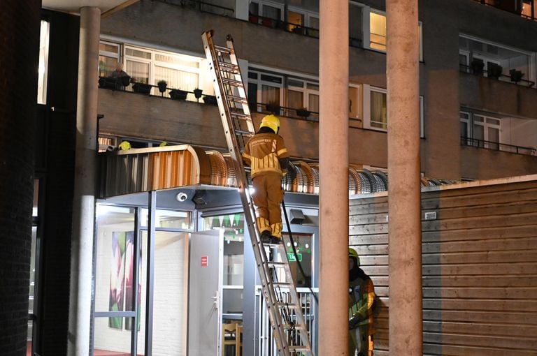 Een brandweerman stond op een ladder om de brand op het afdak van de eerste verdieping te blussen (foto: SQ Vision/Perry Roovers).