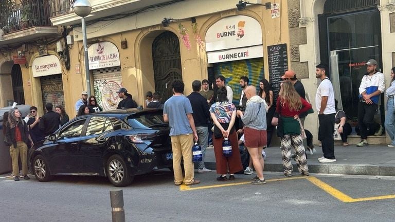 Mensen rondom een auto in Spanje luisterend naar een autoradio voor meer info over de storing (foto: Maarten kortlever).