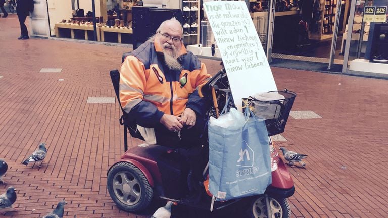 Arnol Kox in zijn scootmobiel terwijl hij de duiven voert.