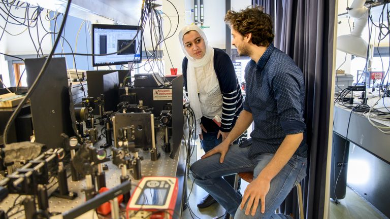 Elham Fadaly (l) en Alain Dijkstra (r) bedienen een optische opstelling om licht-emissie te meten (Foto: Foto: Sicco van Grieken/SURF)