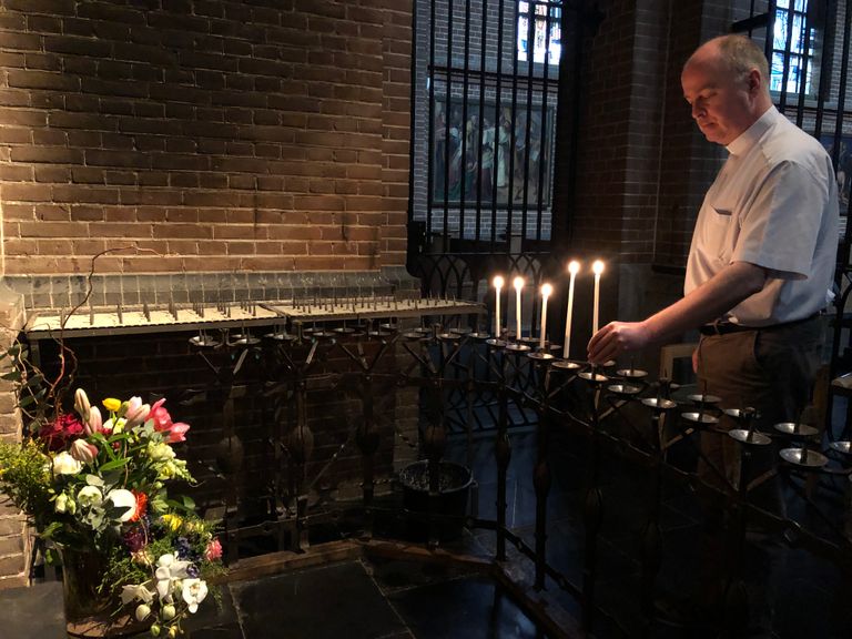 Pastoor John van de Laar steekt een kaarsje aan in de kerk in Uden (Foto: Imke van de Laar)