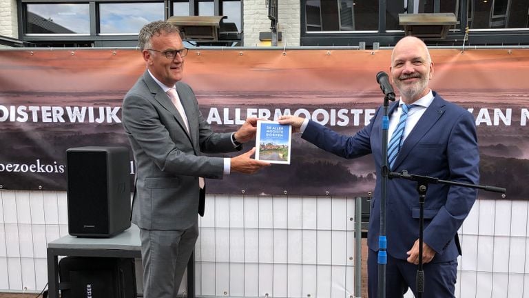 Jürgen Snoeren van de ANWB overhandigt het boek aan burgemeester Hans Janssen.