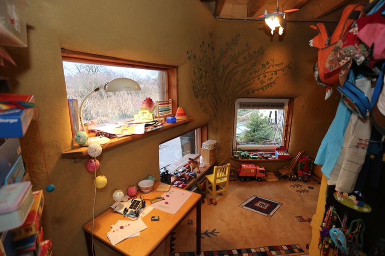 Kinderkamer van Ilja, met een laag raam zodat hij naar buiten kan kijken. Op de muur een boom met echte blaadjes.