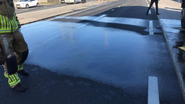 De brandweer spuit de gelekte diesel van de weg