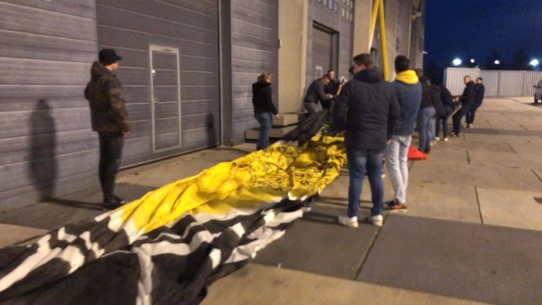 NAC-supporters brengen het enorme spandoek voor de Poolse bevrijders het stadion binnen.