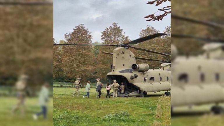 De burgemeester en schooldirecteur worden veilig naar een ronkende Chinook-helikopter gebracht (foto: Niek de Bruijn).