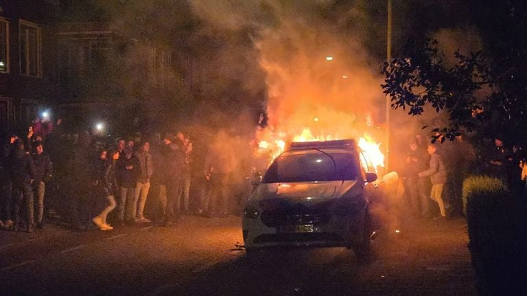 De politie auto stond al snel in lichterlaaie met tientallen mensen er omheen (foto: SQ Vision).