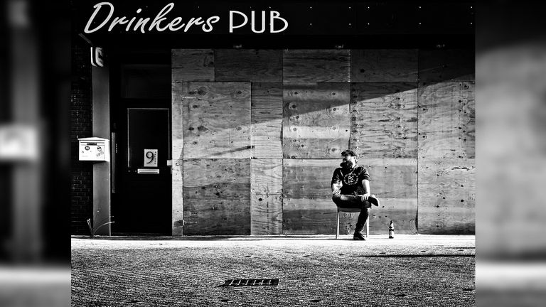 Een man voor café Drinkers Pub, een dag na de rellen in Eindhoven. De ramen zijn dichtgetimmerd (foto: Hildegard Hick).