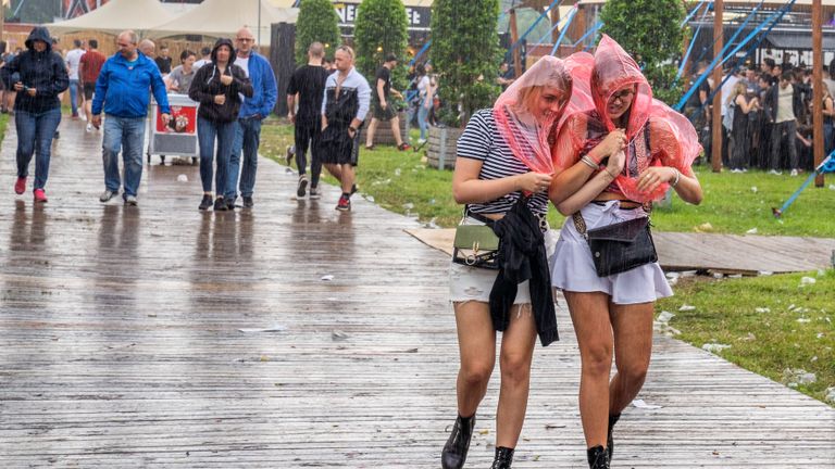 Twee meisjes proberen droog te blijven door een regencape (foto: Dave Hendriks/MaRicMedia).