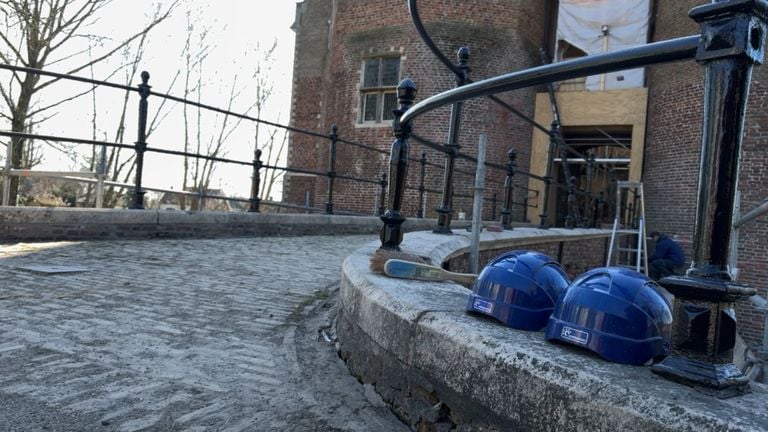 Twee bouwhelmen op een muurtje naast de slotgracht van Kasteel Dussen (foto: Niek de Bruijn).